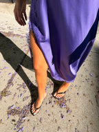 Woman wearing a purple high slit midi dress and black sandals