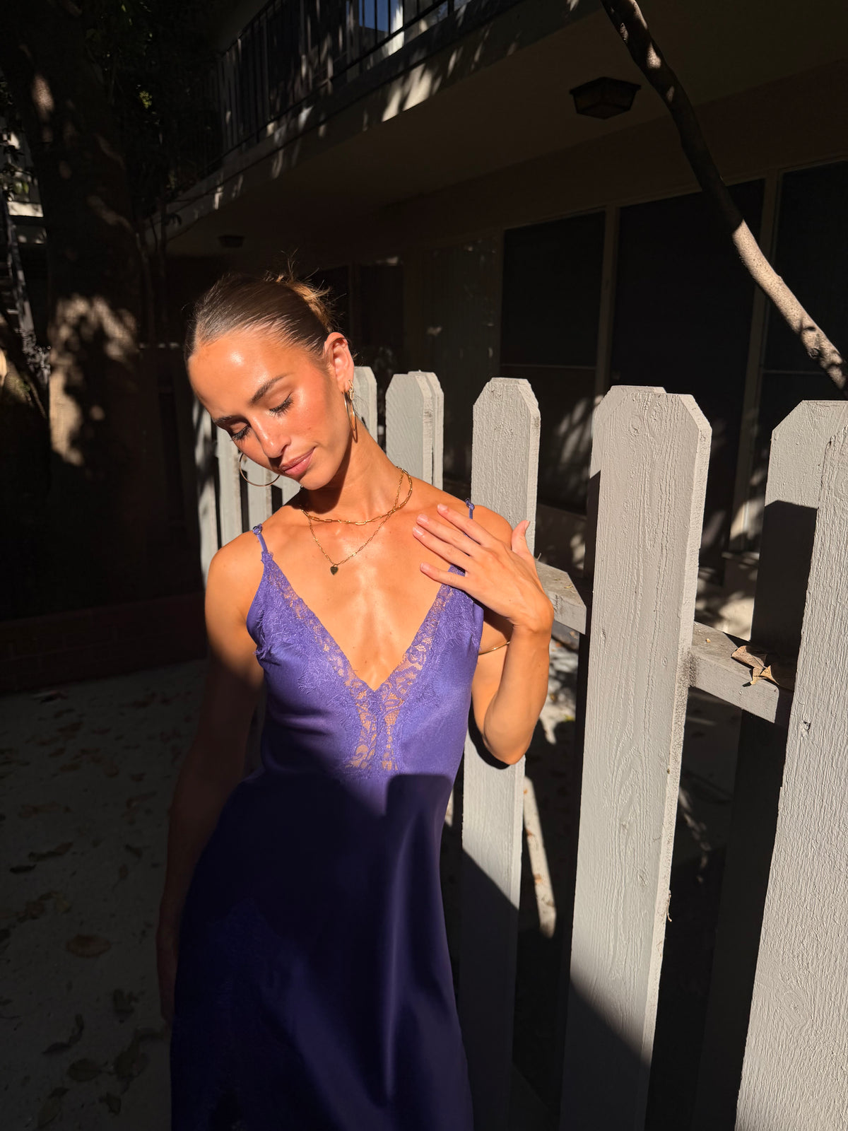 Woman wearing a purple satin lace v-neck midi dress outdoors