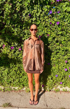 Woman wearing an oversized sheer brown button down blouse outdoors
