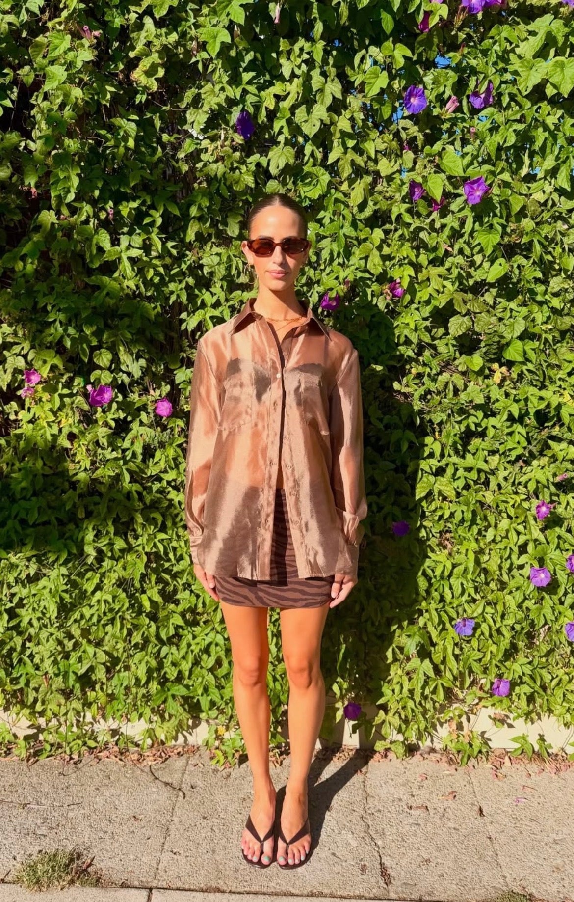 Woman wearing an oversized sheer brown button down blouse outdoors