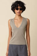 Woman wearing a fitted sleeveless V-neck tank top paired with plaid pants, styled with sunglasses and hoop earrings.