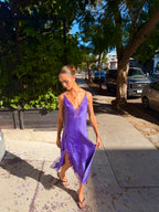 Woman wearing a purple satin lace slit midi dress outdoors