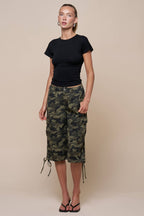 Woman wearing oversized camouflage cargo shorts with drawstring hems and a black top