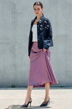 Woman wearing a pink satin midi skirt and embellished navy jacket