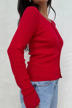Woman wearing a fitted red lightweight women's cardigan with subtle textured eyelet design and long sleeves.
