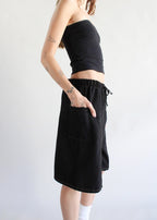 Woman wearing black elastic waist denim shorts with a wide side pocket and tattoos on her arm