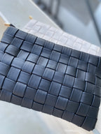Close-up of a woven vegan leather clutch with a detachable strap, suitable for women’s fashion accessories.
