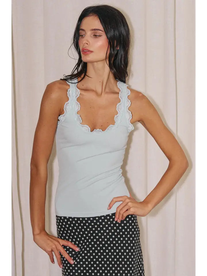 Woman wearing a pale blue lace-trim tank top with a scoop neckline and polka dot skirt