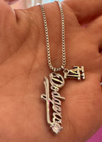 Silver layered necklace with Dodgers script and team logo charms held in hand, women's fashion accessory