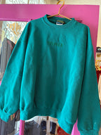 Teal vintage sweatshirt with embroidered "STONER" text, hanging on golden hanger in a women's clothing store.