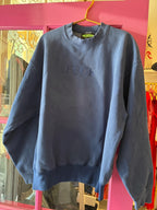 Blue vintage sweatshirt with embroidered text hanging on a yellow hanger, women's casual clothing displayed in store