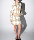 Woman wearing beige and white argyle knit skirt and matching cardigan set in a preppy style outfit for women's clothing