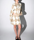 Woman wearing beige and white argyle knit skirt and matching cardigan set in a preppy style outfit for women's clothing