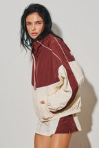 Woman wearing a burgundy and cream colorblock windbreaker jacket