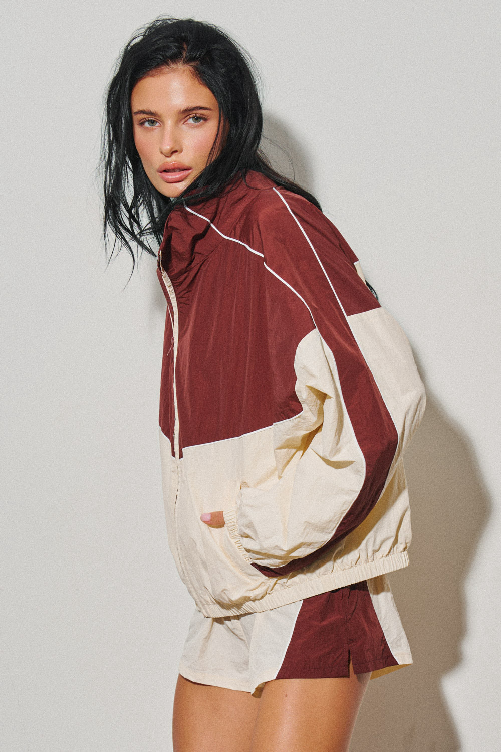 Woman wearing a burgundy and cream colorblock windbreaker jacket