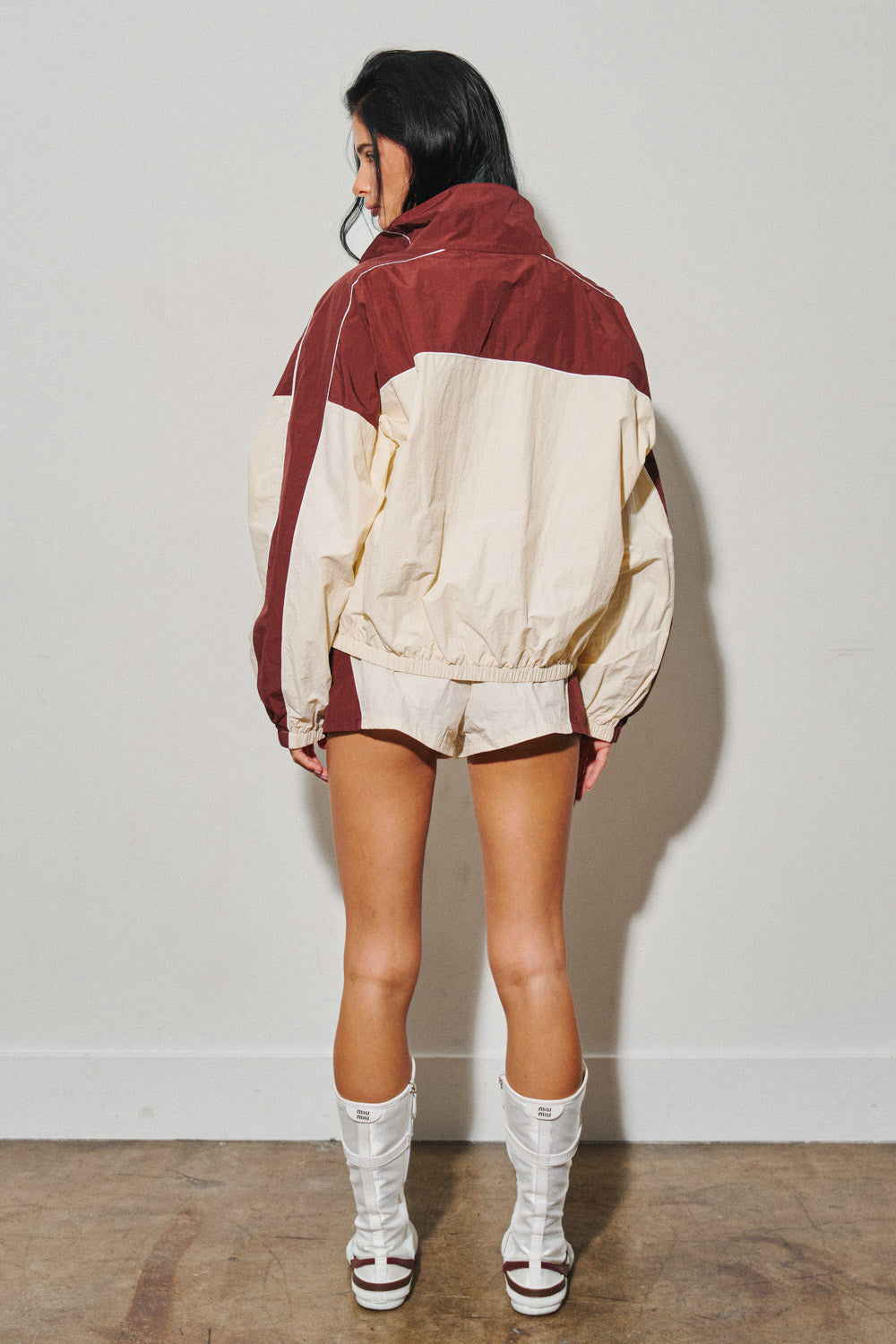 Woman modeling colorblock windbreaker shorts with white boots