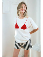 Woman wearing a white short-sleeve tee with red bikini graphic detail and black-and-white striped shorts.