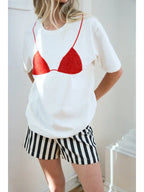Woman wearing white tee with red beaded bikini design and black and white striped shorts in bright room