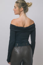 Woman wearing off-shoulder long-sleeve black top paired with high-waisted dark leather pants in women's clothing style