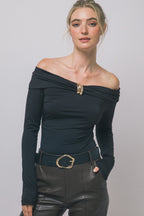 Woman wearing black off-shoulder long-sleeve bodysuit with gold buckle and black belt with gold buckle in women's clothing style