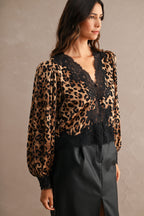 Woman wearing leopard print blouse with black lace trim and long sleeves paired with black skirt