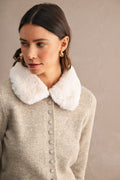 Woman wearing a knit cardigan with a contrasting faux fur collar and button front