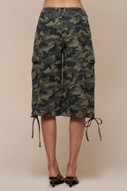 Women's camo cargo shorts with side pockets and adjustable drawstring hems on a model