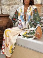 Woman wearing loose, colorful abstract printed pants and matching long-sleeve shirt in relaxed pose
