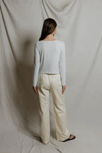 Woman wearing a white and gray striped long sleeve top with cream wide-leg pants against a neutral background