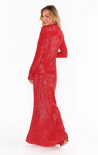 Woman wearing a sparkling red sequin bodycon maxi dress with long sleeves and a turtleneck, posing sideways.