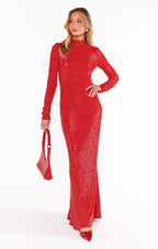 Woman wearing a long red sequin bodycon maxi dress with long sleeves and holding a matching red handbag