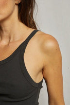 Close-up of a woman wearing a ribbed, dark-colored tank top with thin straps, showcasing textured fabric in women's clothing.