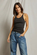 Woman wearing a fitted black ribbed tank top paired with relaxed blue denim jeans against a neutral backdrop