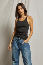 Woman wearing a fitted black ribbed tank top paired with relaxed blue denim jeans against a neutral backdrop