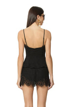Woman wearing a black lace sleeveless top with adjustable straps and matching lace shorts, back view.