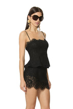 Woman wearing black lace sleeveless top and matching skirt styled with large sunglasses and statement earrings