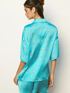 Woman wearing a loose, turquoise lounge top with a swimmer print, shown from the back in women's clothing style.