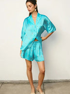 Woman wearing a loose fit azure blue lounge top and matching shorts in lightweight fabric for casual wear.