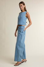 Woman wearing sleeveless denim cropped top with tie back and high-waisted wide-leg denim pants