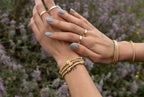 Woman's hands adorned with gold stretch bracelets and rings, showcasing stylish women's jewelry and accessories.