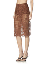 Woman wearing a cappuccino lace midi skirt with floral patterns and high-heeled open-toe sandals.