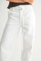 Close-up of women's high-rise white denim wide-leg pants with a slim detachable belt and button closure