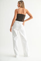 Woman wearing high-rise wide leg white denim pants with a detachable belt shown from the back