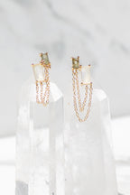 14K gold vermeil earrings with green and white stones connected by delicate gold chains displayed on clear crystals