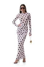 Woman wearing a pink long-sleeve top and matching ruched skirt with large black polka dots in women's clothing style.
