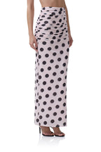Woman wearing a high-waisted long pink skirt with large black polka dots, styled with ruched detailing at the waist