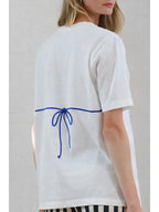 Woman wearing a white tee with a blue tie detail at the back, styled for women's casual clothing.