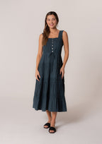 Woman wearing a navy tiered midi dress with lace trim, button front, and tie waist in a studio setting.
