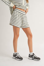 Woman wearing casual striped shorts and matching long sleeve top with sneakers, showcasing women's clothing style.