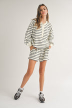 Woman wearing casual cream and black striped shorts and matching long-sleeve top in relaxed fit for women's clothing.